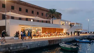 a group of people sitting at a restaurant next to the water at Rosdani Apartment in Palermo