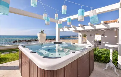 a hot tub on a patio with the ocean in the background at 3 Bedroom Gorgeous Home In Trappeto in Trappeto