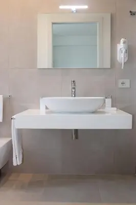 a bathroom with a white sink and a mirror at Coral Sand bed and breakfast in San Vito lo Capo