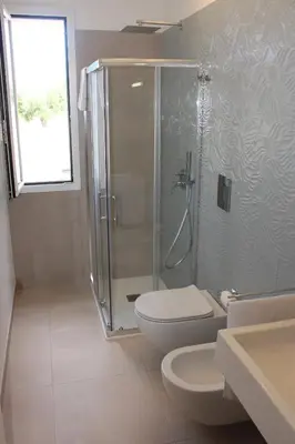 a bathroom with a shower and a toilet and a sink at Coral Sand bed and breakfast in San Vito lo Capo