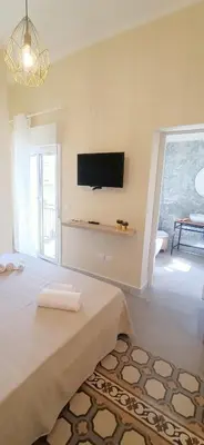 a living room with a bed and a tv on the wall at Domus Maqueda - Pressi Teatro Massimo in Palermo