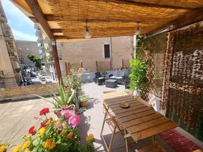 a patio with a wooden table and some flowers at Casetta Polì- Appartamento con terrazza - Centro Storico in Palermo