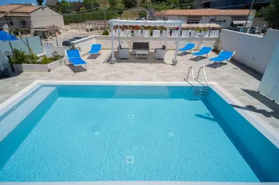 a swimming pool with blue chairs and a patio at holiday inn endless summer in Alcamo