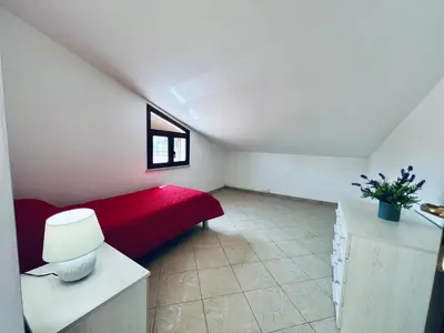 a attic room with a red bed and a window at Villa Genova in Carini