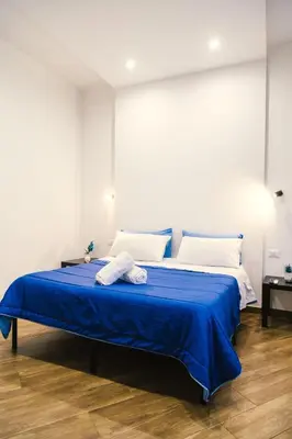 a bedroom with a bed with blue sheets and white pillows at Galka Rooms in Palermo