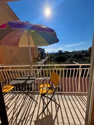 two chairs and an umbrella on a deck at TOURIST HOUSE Le casette di Sofì in Bagheria