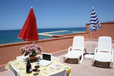 a table with a laptop and chairs and the ocean at GB Case Vacanze Sicilia in Balestrate