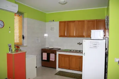 a kitchen with green walls and a white refrigerator at GB Case Vacanze Sicilia in Balestrate
