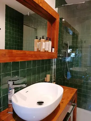 a bathroom with a white sink and green tiles at I Canti Comfort Rooms in Palermo