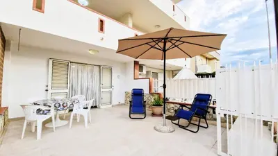 a patio with a table and chairs and an umbrella at Casa Alamar 100 metri dal mare in Alcamo