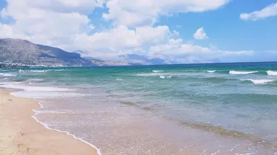 a beach with the ocean and mountains in the background at Casa Alamar 100 metri dal mare in Alcamo