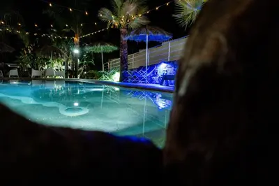 a swimming pool at night with palm trees and lights at RhelizeOne & Spa جميل in Palermo