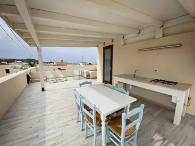 a patio with a white table and chairs on a roof at A Cantunera in San Vito lo Capo