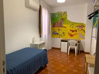 a bedroom with a bed and a desk and a painting at Casavacanze nel blu Maestrale in Isola delle Femmine