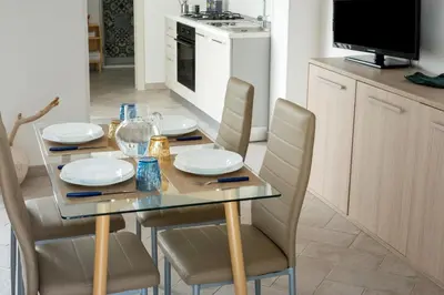 a dining table and chairs with plates and glasses on it at RYS Mondello House in Palermo