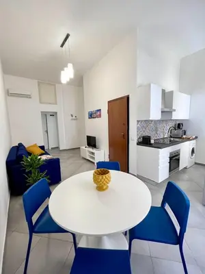 a living room with a white table and blue chairs at Casina al 32 in Palermo