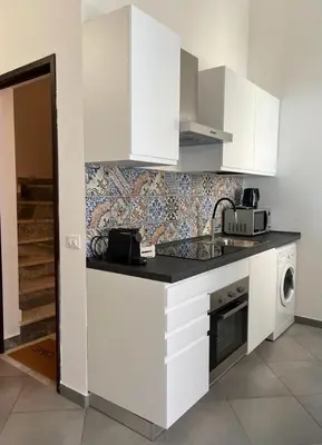 a kitchen with white cabinets and a tile wall at Casina al 32 in Palermo
