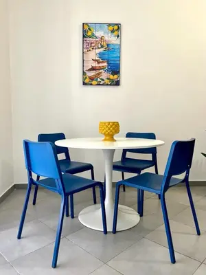 a white table with blue chairs and a vase on it at Casina al 32 in Palermo