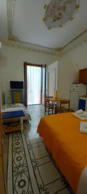 a room with two beds and a table and a kitchen at Casetta Colorata in Bagheria