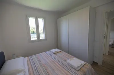 a white bedroom with a bed and a window at Villa Giada - Private pool in Campofelice di Roccella