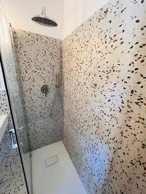 a bathroom with a shower with a wall covered in rocks at Casa Khalesia in Palermo