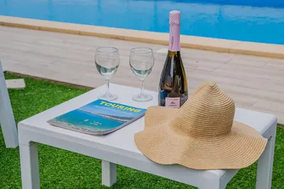 a hat and two glasses and a bottle of wine on a table at Villa Capri - Private pool in Campofelice di Roccella