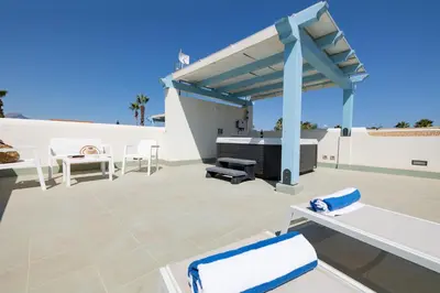 a patio with white chairs and a barbecue grill at Villa Amalfi in Campofelice di Roccella