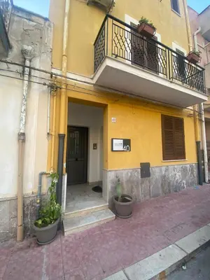a yellow building with two potted plants in front of it at Casa Ciccio in Cinisi