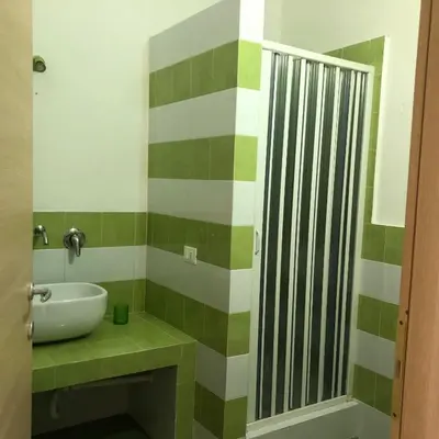 a green and white bathroom with a sink and a mirror at Casa Ciccio in Cinisi