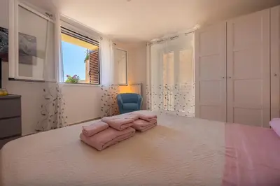 a bedroom with a large white bed with a blue chair at La mia deliziosa Casetta di giù in Termini Imerese