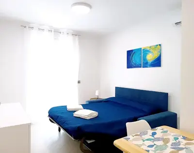 a bedroom with a blue bed and a table at Casa Marinaro in Castellammare del Golfo