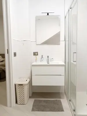 a white bathroom with a sink and a mirror at Casa Marinaro in Castellammare del Golfo