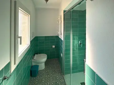 a green tiled bathroom with a toilet and a shower at Solemar Sicilia - Casa Tramonto in Bagheria
