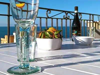 a table with a glass vase and a bottle of wine at Solemar Sicilia - Casa Tramonto in Bagheria