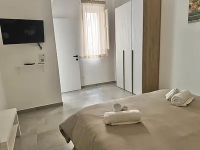 a white bedroom with two towels on a bed at HOLIDAY HOUSE ORLANDO in Palermo