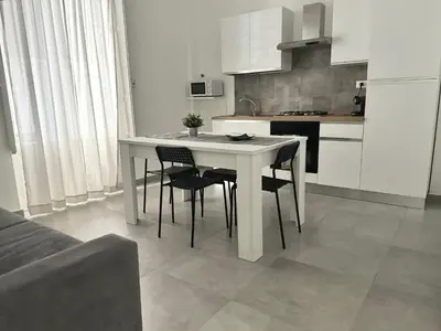 a white kitchen with a table and chairs in it at HOLIDAY HOUSE ORLANDO in Palermo
