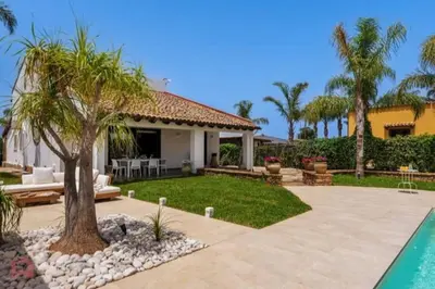 a house with a palm tree in a yard at Posh villa with pool & jacuzzi in Balestrate