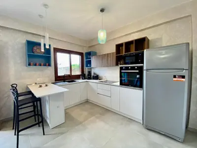 a kitchen with a white refrigerator and a table at Casa Perla Marina sul mare in Castellammare del Golfo