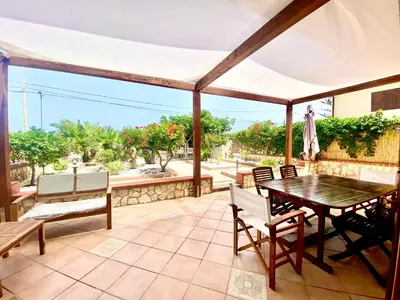 a patio with a table and chairs and an umbrella at Casa Perla Marina sul mare in Castellammare del Golfo