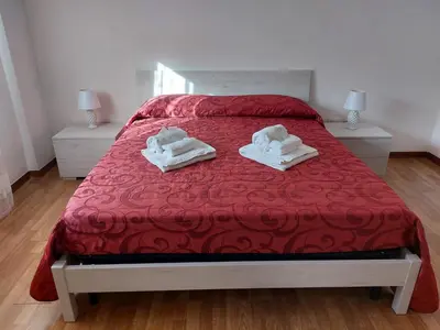 a bedroom with a red bed with towels on it at Kalisa Home, B&B e Casa Vacanza Palermo in Capaci