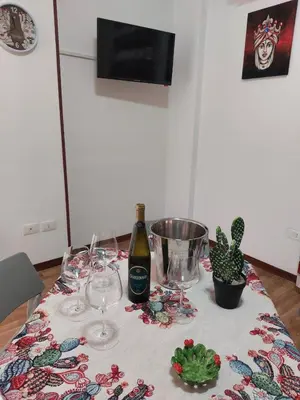 a table with glasses and a bottle of wine and a cactus at Kalisa Home, B&B e Casa Vacanza Palermo in Capaci