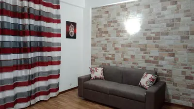 a living room with a couch and a brick wall at Kalisa Home, B&B e Casa Vacanza Palermo in Capaci