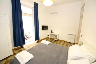 a bedroom with a bed with blue curtains and a window at Thalia in Palermo