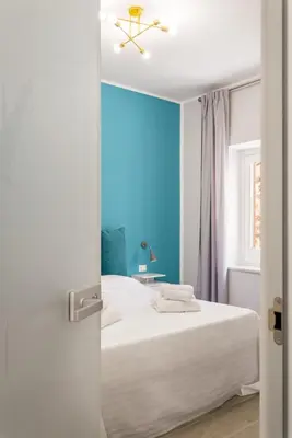 a bedroom with a white bed and a blue wall at LE PORTE DEL KASSARO in Palermo