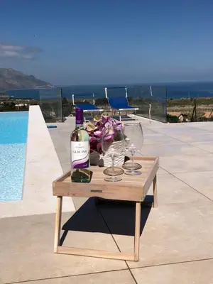 a table with a bottle of wine and glasses on it at Villa MiraScopello in Castellammare del Golfo