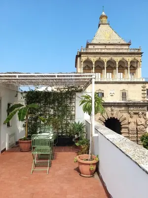 a balcony with chairs and a building in the background at La Porta dei Mori in Palermo