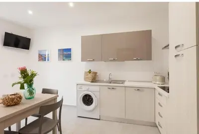 a white kitchen with a washing machine and a table at Holiday House Lady in Terrasini