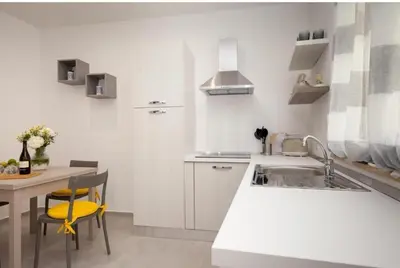 a white kitchen with a sink and a table at Holiday House Monalisa in Terrasini