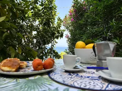 a table with a plate of fruit and coffee cups at Nido del falco in Mondello