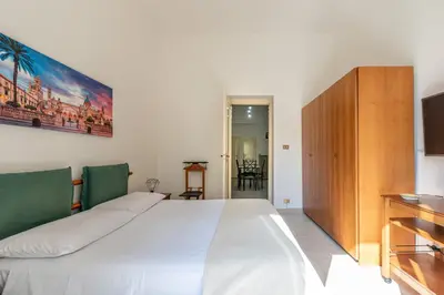 a bedroom with a large white bed and a television at I Mori-holiday apartment in Palermo